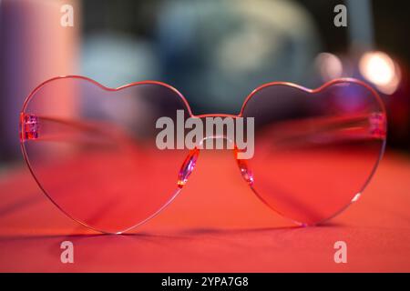 Heart-shaped pink glasses with a blurred colorful background Stock Photo