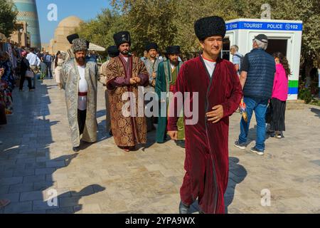 A man in a red robe walks down a street with other men Stock Photo