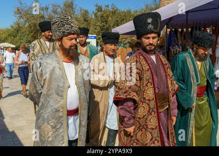 A group of men wearing traditional clothing and hats are walking Stock Photo