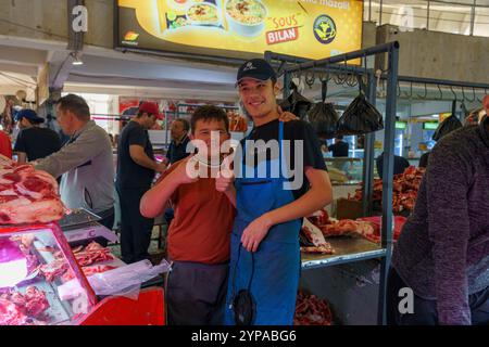 Two young men pose for a picture in front of a meat market Stock Photo