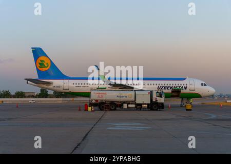 A large Uzbekistan airplane is parked on the tarmac Stock Photo