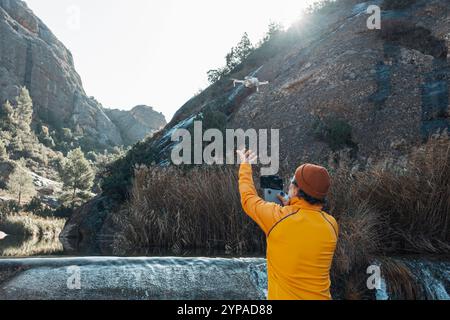 Traveler flying a drone in a forest area using the remote controller. Stock Photo