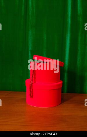Red velvet stacked gift boxes with red tinsel and green drapes Stock Photo