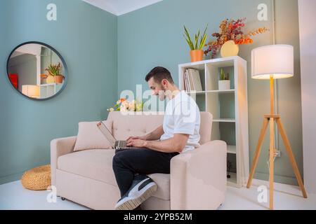 Man working on laptop in cozy living room Stock Photo