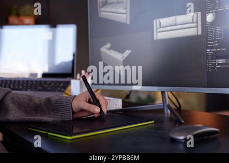 Individual using graphic tablet for creating detailed 3D models in modern design studio. Computer screens displaying renders of sofa models in various perspectives Stock Photo