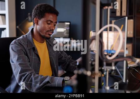 Engineer concentrating on writing code at workstation with computer and modern equipment in office setting Stock Photo