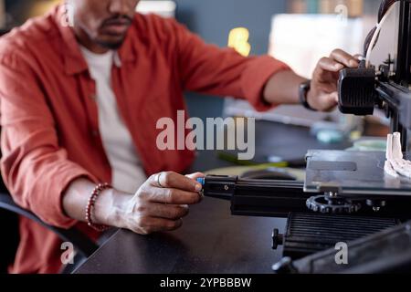 Person operating advanced 3D printer in a modern workspace, focusing on the machine's settings. Detailed components and environment visible in the background Stock Photo