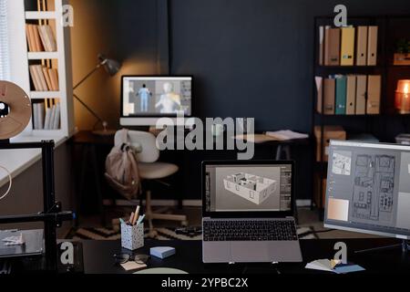 Design studio with various computer screens displaying 3D model renderings, showcasing detailed interior layouts and modern digital design equipment on large desks Stock Photo