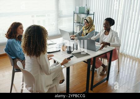Collaborating in Modern Office Setting with Laptop Use Stock Photo