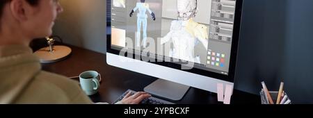 Person working on computer, designing intricate 3D character model with detailed textures and colors visible on screen. Desk includes mug, lamp, and organized stationery items Stock Photo