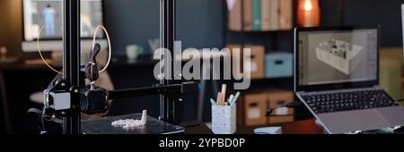 3D printer in a technologically advanced workspace creating an intricate object. Background with open laptop, pencil holder, and shelves filled with organized items Stock Photo
