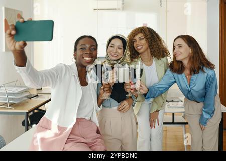 Smiling Colleagues Taking Group Selfie in Office Stock Photo