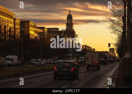 Berlin erwacht: Sonnenaufgang am Frankfurter Tor, Aufnahme des Frankfurter Tors bei Sonnenaufgang. Die aufgehende Sonne taucht die Berliner Straßen in warmes Licht. Berlin Berlin Deutschland *** Berlin wakes up Sunrise at Frankfurter Tor, photo of Frankfurter Tor at sunrise The rising sun bathes the streets of Berlin in warm light Berlin Berlin Germany Stock Photo