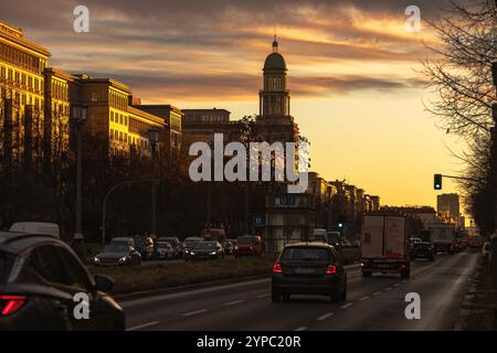 Berlin erwacht: Sonnenaufgang am Frankfurter Tor, Aufnahme des Frankfurter Tors bei Sonnenaufgang. Die aufgehende Sonne taucht die Berliner Straßen in warmes Licht. Berlin Berlin Deutschland *** Berlin wakes up Sunrise at Frankfurter Tor, photo of Frankfurter Tor at sunrise The rising sun bathes the streets of Berlin in warm light Berlin Berlin Germany Stock Photo