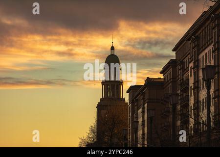 Berlin erwacht: Sonnenaufgang am Frankfurter Tor, Aufnahme des Frankfurter Tors bei Sonnenaufgang. Die aufgehende Sonne taucht die Berliner Straßen in warmes Licht. Berlin Berlin Deutschland *** Berlin wakes up Sunrise at Frankfurter Tor, photo of Frankfurter Tor at sunrise The rising sun bathes the streets of Berlin in warm light Berlin Berlin Germany Stock Photo