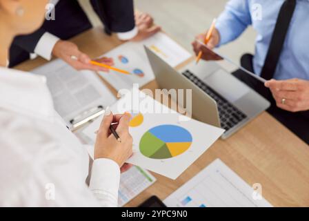 Team discussing document with pie charts close up, business people analyzing data of survey Stock Photo