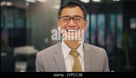 Business, face and laughing with mature man in office for career development or job satisfaction. Funny, glasses and proud with happy Japanese lawyer Stock Photo