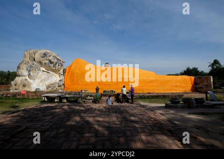 Tourists admiring the giant reclining buddha statue covered with an orange cloth at wat lokayasutharam temple in Ayutthaya historical park Stock Photo