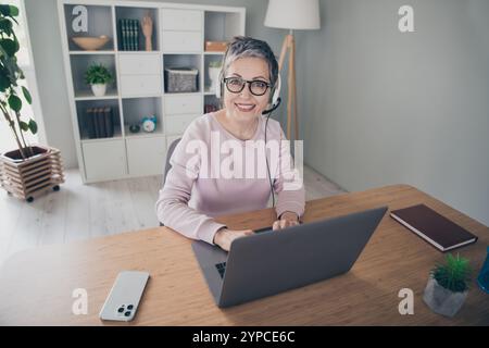 Photo of positive good mood woman dressed pink sweatshirt earphones typing modern gadget indoors house apartment room Stock Photo
