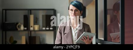 Banner of confident businesswoman with tablet looking at camera while analyzing online financial data in office Stock Photo