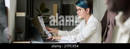 Banner of young female trader with financial paper typing on laptop keypad while analyzing economical data by her workplace Stock Photo