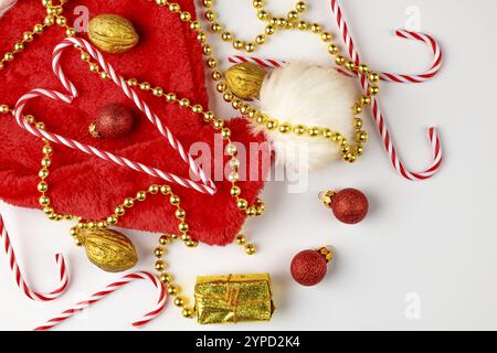 Christmas hat with candy canes, golden pearl necklace and nuts on a white background Stock Photo