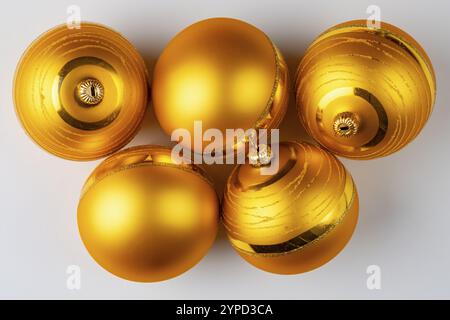 Five golden Christmas baubles lie on a white surface Stock Photo