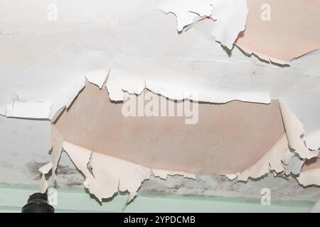 Peeling Damaged Flaking and Falling Down Paint on a Ceiling in a Damp Bathroom Stock Photo
