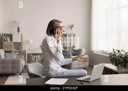 Busy mature entrepreneur woman discussing business project on mobile phone Stock Photo