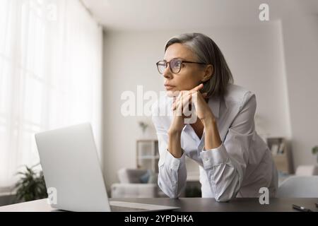 Serious pensive business woman in glasses working at laptop Stock Photo