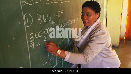 Side view close up of a middle aged African female school teacher standing at the front of the class Stock Photo