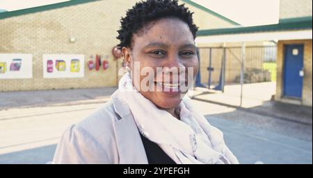 Portrait close up of a middle aged African female school teacher with short spiky hair turning and l Stock Photo