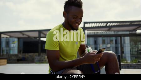 Front view of African american basketball player using mobile phone in basketball court Stock Photo