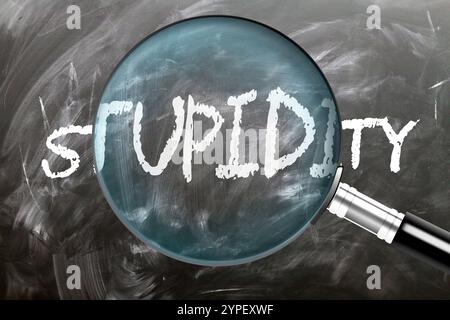 Stupidity - learn, study and inspect it. Taking a closer look at stupidity. A magnifying glass enlarging word 'stupidity' written on a blackboard Stock Photo