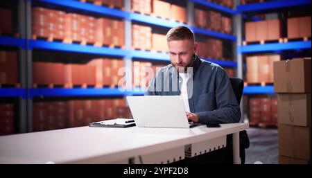 Business Man Using Laptop Computer In Warehouse For Inventory Management Stock Photo