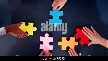 High Angle View Of Businesspeople Hand Solving Jigsaw Puzzle Stock Photo