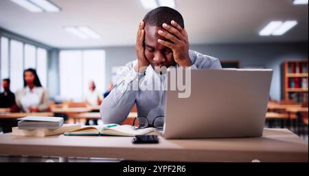 Bored Man In Classroom Using Computer Technology. Laptop In Education Stock Photo