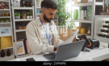 Young hispanic man with beard working on laptop in a decorated home decor store interior Stock Photo