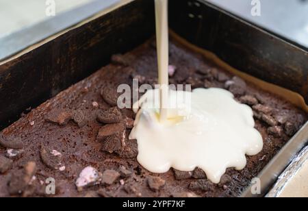 Making a cake, pouring mousse into a chocolate sponge cake with cookie crumbs Stock Photo