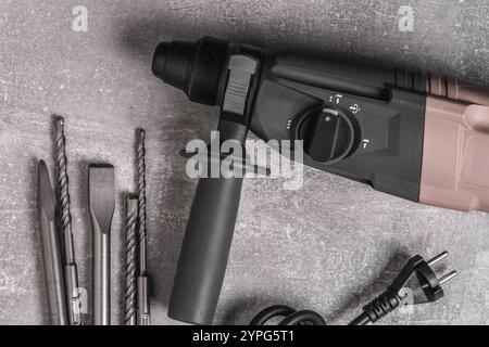 Electric perforator with various drills on concrete on gray concrete background Stock Photo