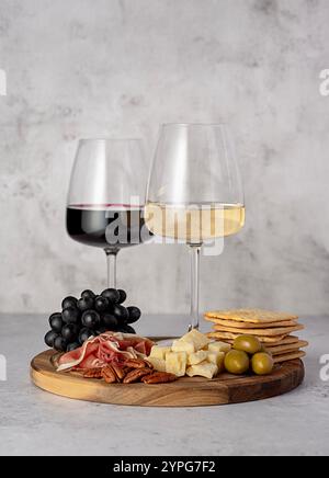 Food photography of red and wine, cheese parmesan, prosciutto, olives, pecan, grapes, crackers, wine glasses, assortment, party meal, romantic date Stock Photo