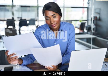 Busy African American business woman working on laptop checking documents. Stock Photo