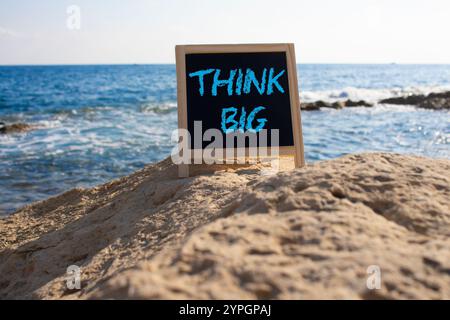 Think big symbol. Concept words Think Big on black chalk background. Beautiful sea background. Business and Think big concept. Copy space. Stock Photo
