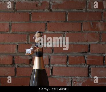 An opened bottle of sparkling wine with a cork and a muzzle on the neck of the bottle. Stock Photo