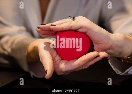 Hands Holding a Red Heart Stress Ball in a Close-Up Setting. Stock Photo