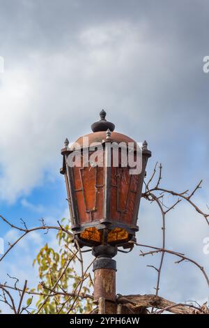 Old rusty lantern between branches against the sky, daytime Stock Photo