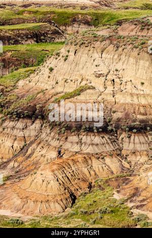 A rocky hillside with a person standing on it. The person is looking down at the ground Stock Photo