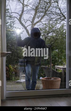 Symbolic image of burglary, perpetrator spies on a flat from the garden side, during the day Stock Photo