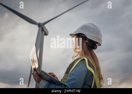 An engineer is actively monitoring the operations of wind turbines using a laptop while working in the renewable energy field, ensuring efficiency and Stock Photo
