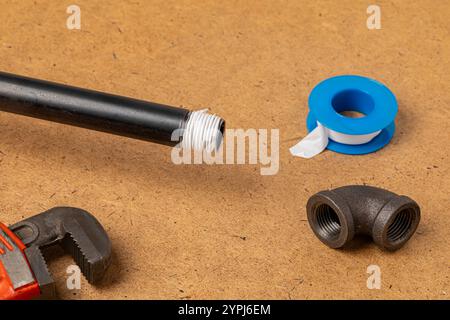 Installing thread sealant tape on black iron plumbing pipe. Plumbing, home maintenance, repair and remodeling concept. Stock Photo
